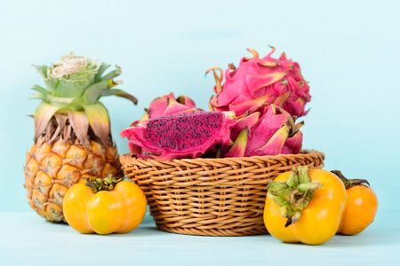 Tropical fruits (persimmon, pineapple and dragon fruit) on pastel backgroundの写真素材