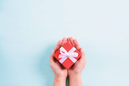 Hands holding gift box on pastel backgroundの写真素材