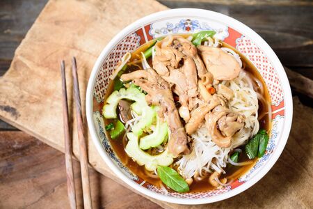 Rice noodles soup with stewed chicken wing and feet in a bowl with chopsticksの写真素材