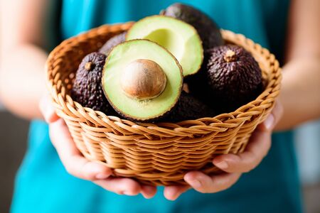 Hand holding basket of hass avocado fruitの写真素材