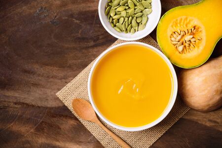 Butternut squash soup and pumpkin seed on wooden background, top viewの写真素材