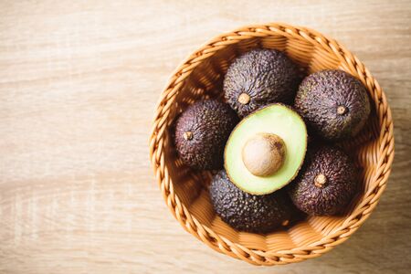 Ripe hass avocado fruit in basket on wooden backgroundの写真素材