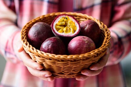 Fresh passion fruit in basket holding by handの写真素材