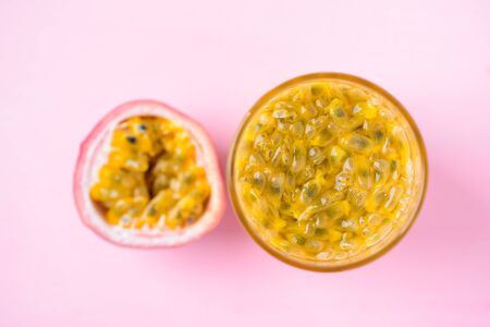 Fresh passion fruit and juice in glass on pink background, tropical drinkの写真素材
