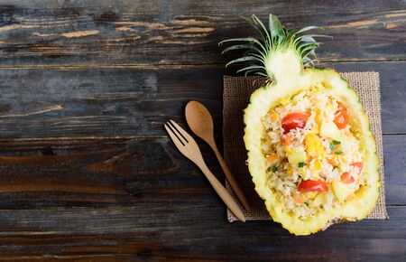 Thai food, pineapple fried rice in pineapple fruit bowl on wooden backgroundの写真素材