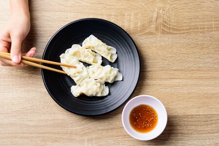 Steamed wonton dumpling stuffed with minced pork and shrimp eating with sesame oil sauce by chopsticks, Asian foodの写真素材