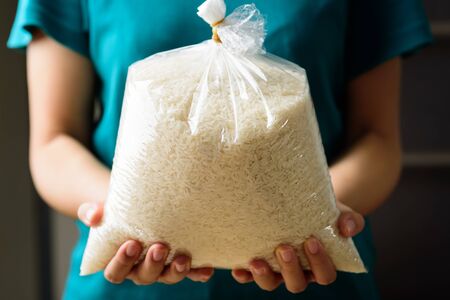 Organic Thai Jasmine rice grain in plastic bag holding by hand for givingの写真素材