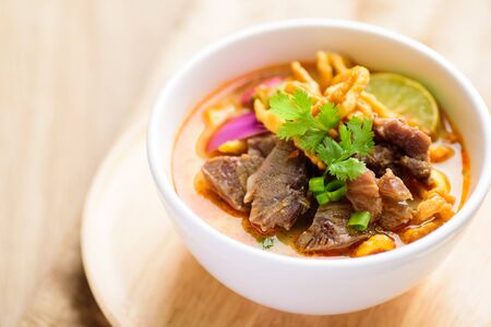 Northern Thai food (Khao Soi), spicy curry noodles soup with coconut milk and beef in a bowlの写真素材