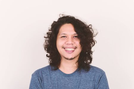 Portrait of happy Asian man face smiling on white concrete wallの写真素材