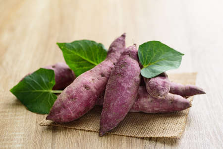 Raw purple sweet potatoes on wooden backgroundの写真素材