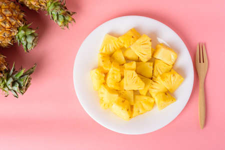Sliced pineapple fruit on white plate with fork ready to eating on pastel pink background, Tropical fruitの写真素材