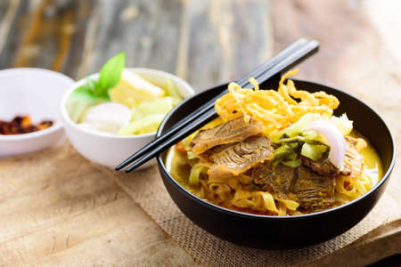 Northern Thai food (Khao Soi), Spicy curry noodles soup with beef eating with crispy egg noodles,...