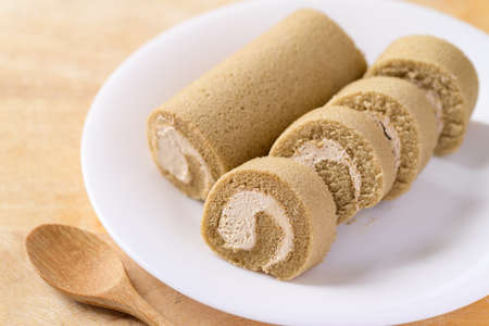 Coffee roll cake on white dish with spoon ready to eating