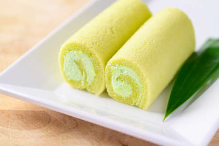 Pandan roll cake with pandan leaf on white dish