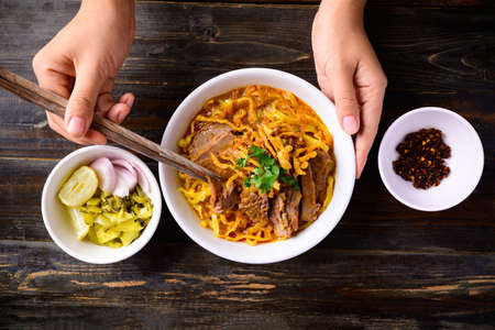 Northern Thai food (Khao Soi), Spicy curry noodles soup with beef eating with pickled mustard, shallot, lime and ground chili fried in oilの写真素材