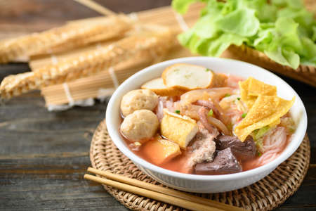 Thai food (Yen Ta Fo), Rice noodles soup with red sauce and fish tofu, pork ball and fried wonton in...