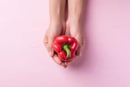 Red bell pepper holding by hand on pink background, Top viewの写真素材