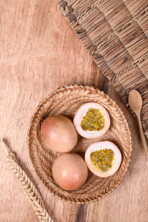 Fresh passion fruit in a basket with spoon on wooden background, Tropical fruit, Top view