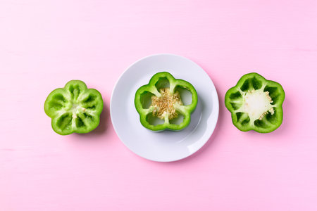 Sliced green bell peppers on white plate with pink background, Top viewの写真素材