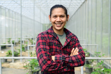 Asian young man farmer smile and arms crossed in organic fig tree greenhouseの写真素材
