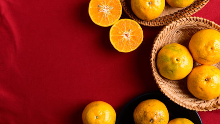 Tangerine orange fruit in bamboo basket on red background, Chinese New Year conceptの写真素材