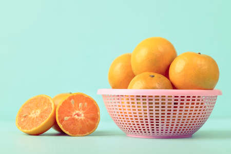 Fresh tangerine orange fruit in a basket on color backgroundの写真素材