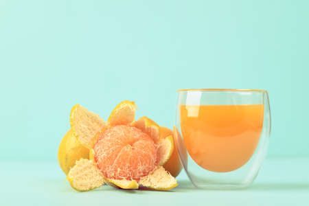 Fresh tangerine orange fruit and juice in glass on color backgroundの写真素材