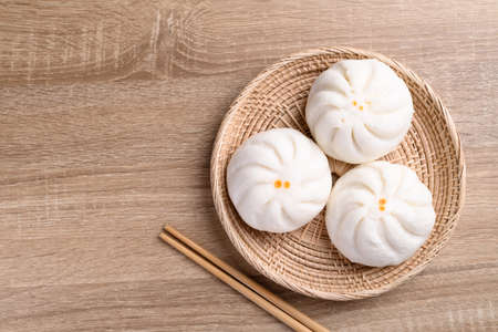 Steamed buns stuffed with minced pork and chopsticks on wooden table, Asian foodの写真素材