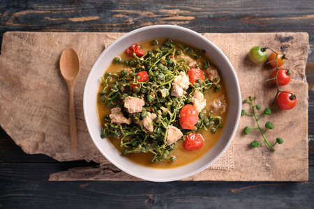 Northern Thai food (Kaeng Sa Lae), Spicy soup Broussonetia Kurzii with pork and tomatoes in a bowl on wooden background, Seasonal food in North Thailandの写真素材