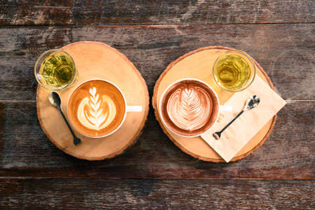 Cup of latte art coffee and chocolate art with hot tea on wooden table, Top viewの写真素材