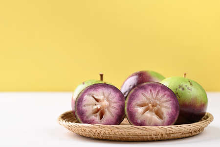 Ripe star apple fruit in a bamboo basket on white and yellow background, Tropical fruitの写真素材