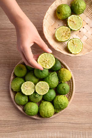 Fresh bergamot fruit in a basket holding by woman hand on wooden background, Food ingredients and extract used for medicine, tea, perfumes and cosmeticsの写真素材