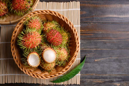Ripe rambutan fruit in a basket on wooden background, Rambutan is tropical fruit and native Southeast Asia, juicy and sweet tasteの写真素材