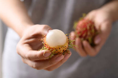 Ripe rambutan fruit holding by woman hand, Rambutan is tropical fruit and native Southeast Asia, juicy and sweet tasteの写真素材