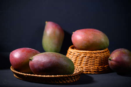 Fresh palmer mango in a basket on black background, Tropical fruitの写真素材