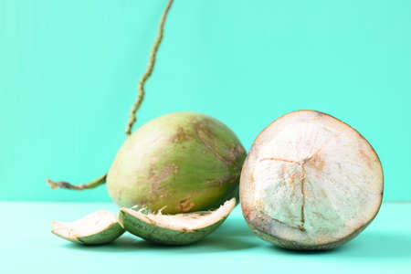 Peeled young coconut fruit on green color background, Summer tropical fruit