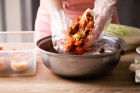 Woman making kimchi cabbage in a big bowl, Popular homemade Korean traditional fermented side dish foodの写真素材