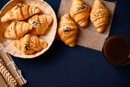 French croissant with black sesame seeds and coffee cup on black background, morning breakfast, Top viewの写真素材