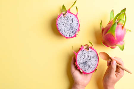 Dragon fruit or pitaya holding by woman hand with spoon for eating on yellow background, Tropical fruitの写真素材
