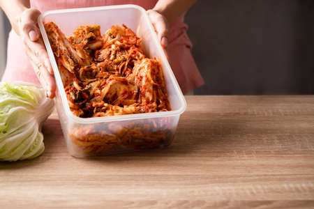Kimchi cabbage in food container holding by hand, Popular homemade Korean traditional fermented side dish foodの写真素材