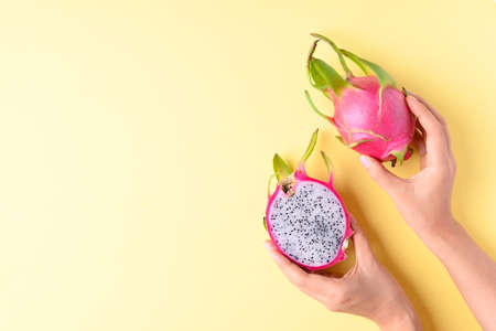 Dragon fruit or pitaya holding by woman hand on yellow background, Tropical fruitの写真素材