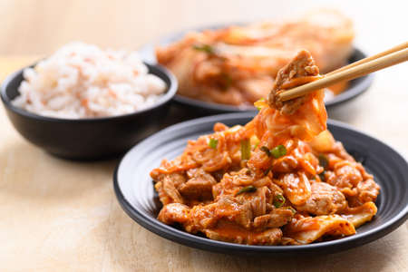 Stir-fried kimchi cabbage with pork eating with cooked rice by chopsticks, Homemade Korean foodの写真素材