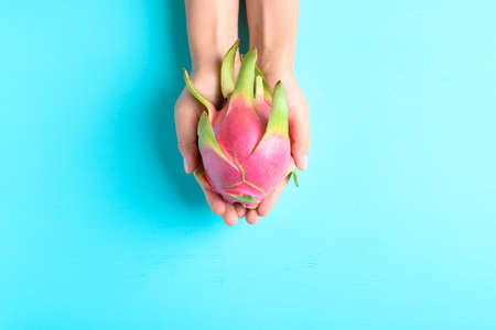 Dragon fruit or pitaya holding by woman hand on color background, Tropical fruitの写真素材