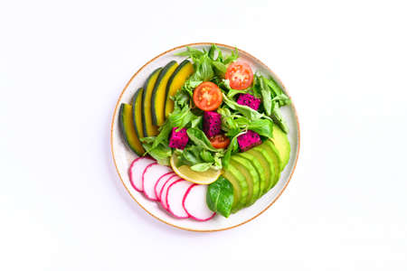 Vegan salad fruits and vegetables dish with avocado, dragon fruit, radish, pumpkin, tomato, corn salad, lettuce, mizuna and lemon on white background. Healthy foodの写真素材
