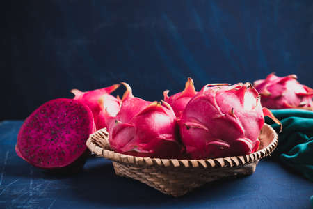 Ripe red dragon fruit or pitaya in bamboo basket on blue background, Tropical fruitの写真素材