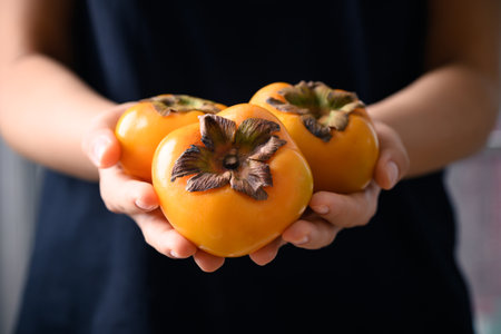 Ripe persimmon fruit holding by woman hand, Healthy Eatingの写真素材