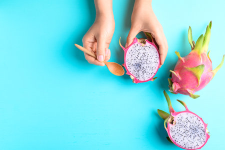 Dragon fruit or pitaya holding by woman hand with spoon for eating on color background, Tropical fruitの写真素材