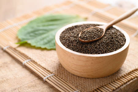 Perilla seeds in a bowl with spoon on wooden background, Healthy herbal seed ingredients in Asian...