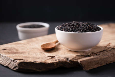 Black sesame seeds in a white bowl with spoon on wooden, Still Life