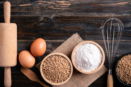 Kitchen utensil for bakery cooking and food ingredients (wheat grain, flour and egg) on wooden background, Table top viewの写真素材